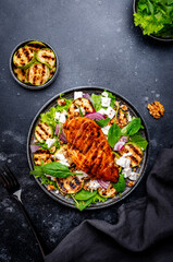 Foodie grill salad with zucchini and chicken, feta cheese, walnuts, red onion and spinach, black background, top view