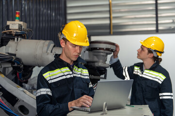 Fototapeta premium Engineer standing by robotic arm and operating machine in industry factory, technician worker check for repair maintenance electronic operation