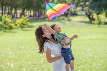 Asian family having fun mother and her son playing with kite in the park together