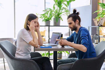 Serious sad upset young couple sitting together in cafeteria