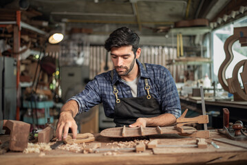 Luthier creating a guitar, clamps on the body of a guitar under construction improving glue adhesion