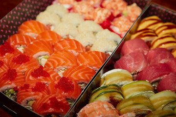 Sushi rolls Philadelphia close-up in black packing boxes in warm light blurred background, blur Sushi in soft warm light, culinary artwork