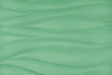 Plaster wall with volumetric relief surface wavy form pattern, green gypsum texture panel.