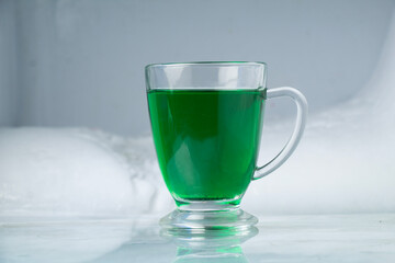 Green cocktail drink in glass cup, single green cocktail, ice cooler background