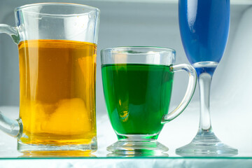 orange beer glass and green beer glass and blue wine glass on glass table bottom view, party bar set drinks