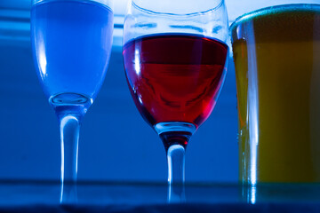 a glass of red wine is next to two glasses of wine.