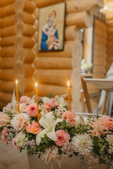 Three Burning Candles Amidst Floral Arrangements in a Wooden Church