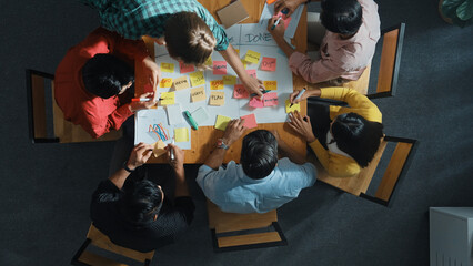 Top view of people writing and making scrum task board while writing marketing and planning strategy at colorful sticky notes. Smart team manage work performance by using kanaban board. Convocation.