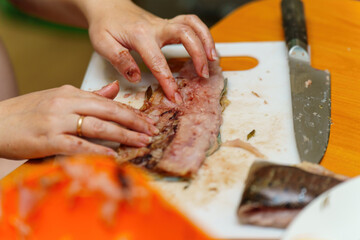 Delicate hands skillfully navigate through fish, meticulously removing bones to prepare a fresh fillet, highlighting the artistry and care in culinary preparation