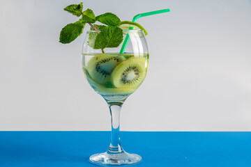 Non-alcoholic cocktail kiwi lime and mint in a glass with a straw on a wooden table
