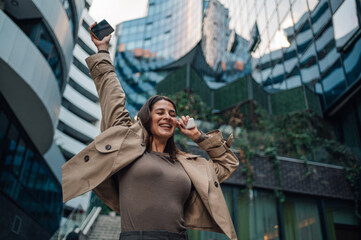 Happy businesswoman celebrating success with smartphone in city