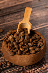 Coffee beans, close-up coffee beans in dark wooden bowl on wooden background.
