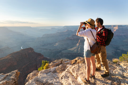 Portrait of happy young couple having fun on their hiking trip. Caucasian and asian hiker couple enjoying themselves on summer vacation. They are watching nature with binoculars.