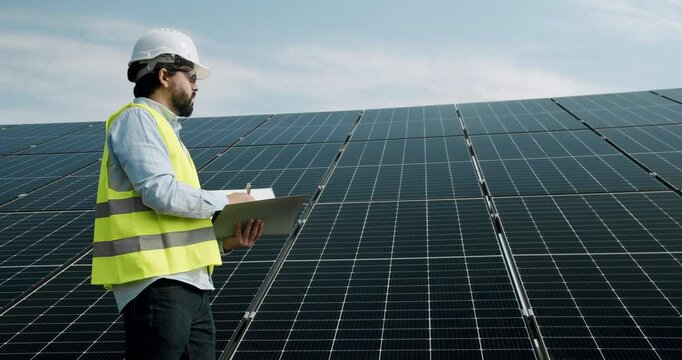 Checking the panels at solar energy installation. Solar cells will be an important renewable energy of the future. The technician in uniform makes notes in the notebook.