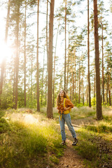 Fototapeta premium Young woman went on a hike in the forest feeling free and full of energy. Autumn landscape.