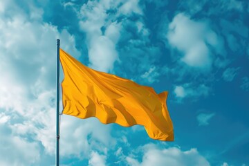 A bright yellow flag waving high in the clear blue sky