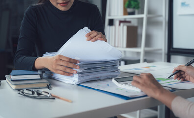 Businesswoman reviewing paperwork:  A close-up shot of a businesswoman meticulously reviewing a...