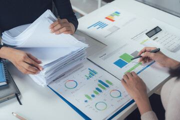 Business Collaboration: Two business professionals meticulously review financial documents and data, engaging in a collaborative discussion to analyze and strategize for success.