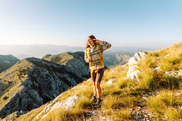 Naklejka premium Woman tourist standing at mountains with backpack admiring landscape. Nature, active life, travel.