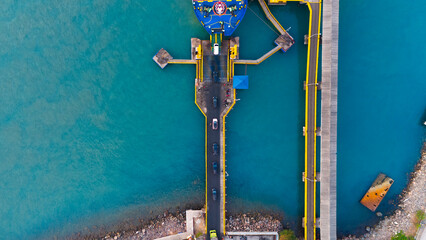 Aerial view of a vibrant ferry dock showcasing the dynamic interplay of bold colors and geometric arrangement between ship, sea, and infrastructure