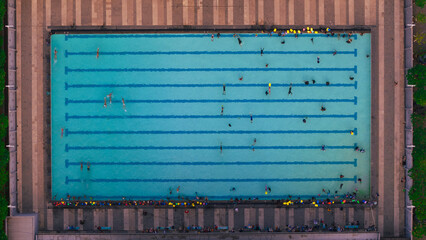 Aerial view of swimmers in a pool creating a vibrant pattern of movement and leisure