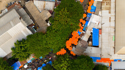 A vibrant aerial view captures a bustling outdoor market, where a serpentine parade of orange...