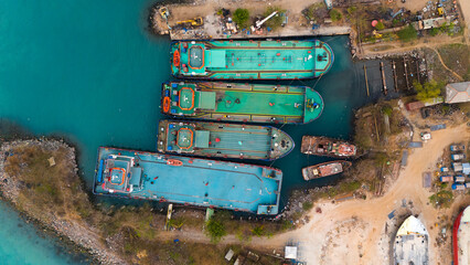 Aerial view of colorful cargo ships docked at a bustling industrial port showcasing the vibrant hustle of maritime logistics