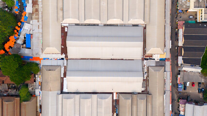 Top-down view capturing the intricate patterns and symmetry of industrial warehouse roofs, surrounded by urban life