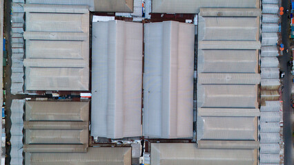 Capture the industrial symmetry from above, showcasing the geometric patterns and textures of warehouse rooftops in an urban setting