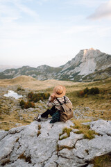 A woman stands on rocky terrain, gazing out at the breathtaking landscape before her. Autumn. Active lifestyle.