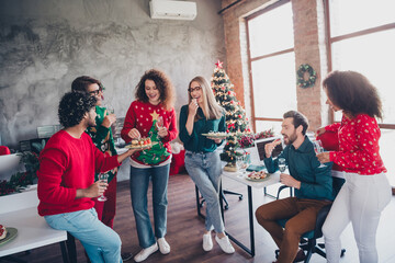 Full body photo of cheerful young people colleagues eat snacks celebrate cozy christmas party decor...