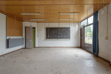 Abandoned classroom in a public accessible school building, with plug sockets hanging out of wooden ceiling