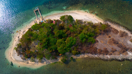 Aerial view of a serene tropical island oasis with lush greenery and a sandy beach hugged by crystal clear waters