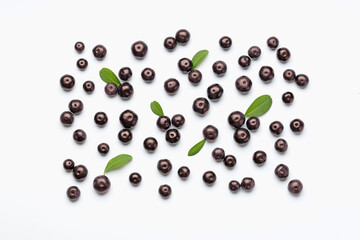 Ripe acai berries and leaves on white background, flat lay