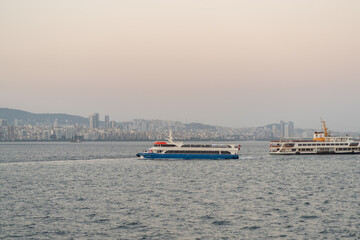 Obraz premium Ferry boats navigate the waters near Istanbul at dusk, with the city skyline glowing in the background, creating a serene atmosphere