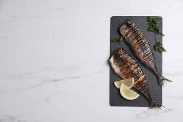 Delicious grilled mackerel, parsley and lemon on white marble table, top view. Space for text