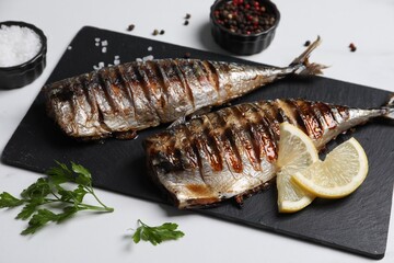 Delicious grilled mackerel, parsley, spices and lemon on white table