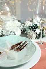 Christmas place setting with plates, cutlery and festive decor on table