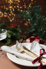 Christmas place setting with plate, napkin, cutlery and festive decor on brown table