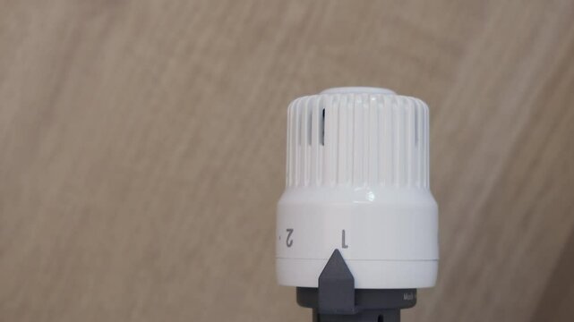 Thermostatic valve being adjusted to a lower setting as winter sets in. Could be reversed to decrease the heat. Male hand. Lockdown. Could be reversed to increase the temperature with copy space