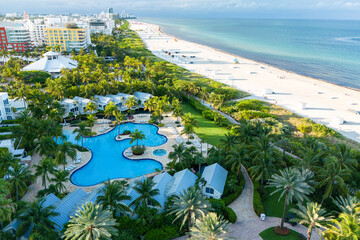 Tropical beachfront resort with vibrant skyline featuring skyscrapers, pools, clear water palm trees