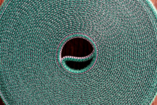Roll of green nylon hook and loop fastener or velcro tape for garden or home, closeup. Velcro tape is used in the garden to support plants to sticks