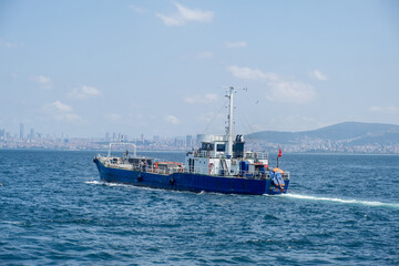 A blue cargo boat navigates through clear waters near Istanbul under a bright sky
