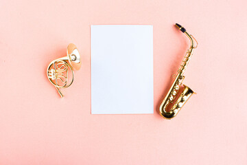 Toy music instruments and white mockup blank on pink background, top view, copy space for the text