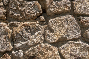 Textured stone wall featuring irregularly shaped rocks in natural hues, set against a weathered...