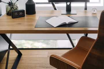 Modern workspace setup with an open notebook on a wooden desk in a bright office environment
