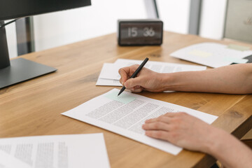 Person reviewing documents and writing notes in office