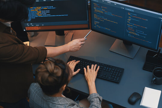 Top view of IT developers discussing with point to intelligent website development coder system running data online two screens information technology at neon light room at modern office. Infobahn.