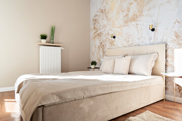 Modern bedroom with textured wallpaper with pattern. Bright interior of room with beige pillow and comfortable bed. New apartment.