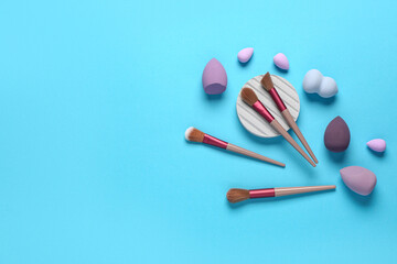 Makeup sponges and brushes on blue background